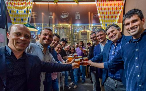 Grupo de pessoas brindando com copo de cerveja em microcervejaria
