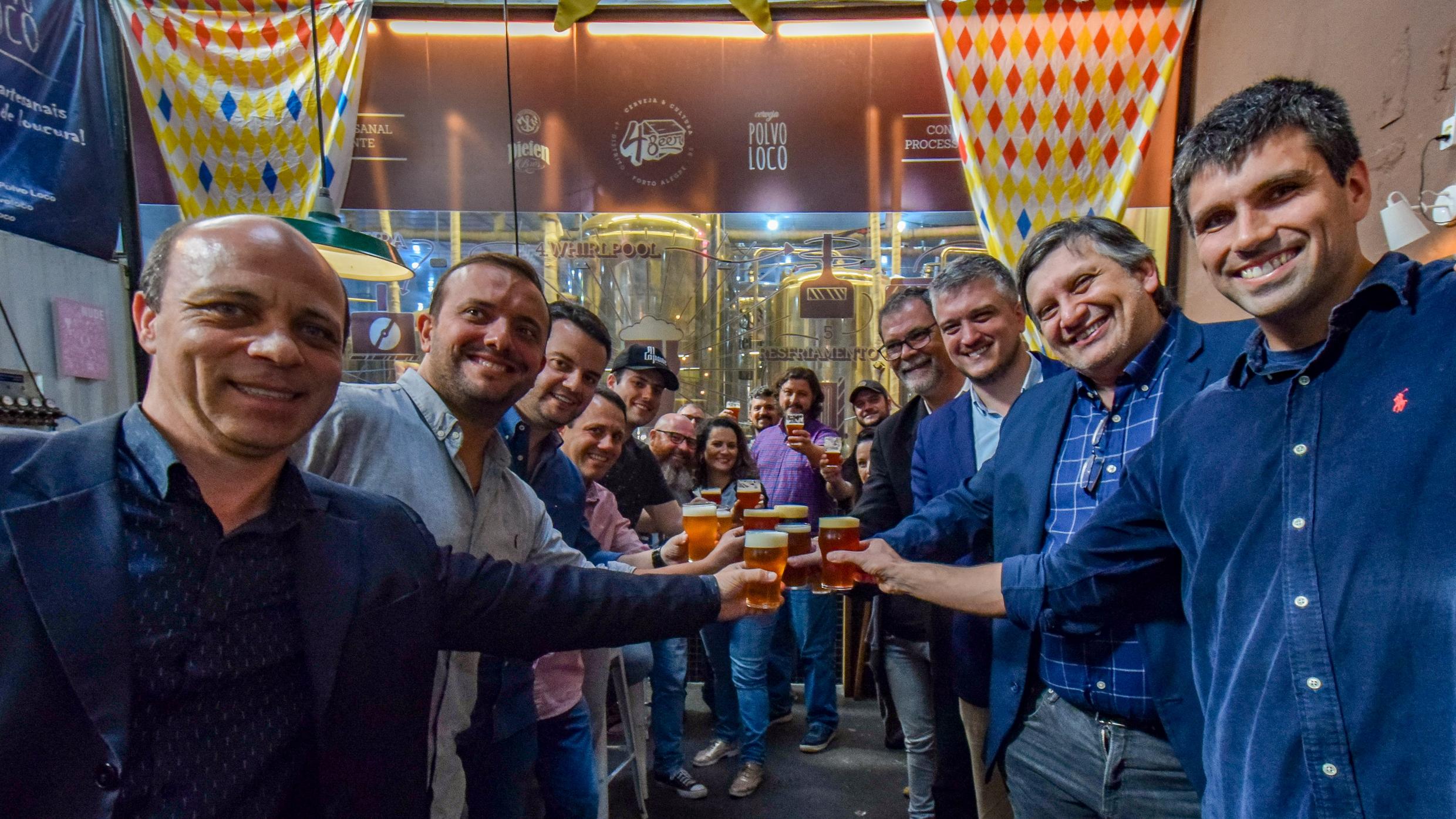 Grupo de pessoas brindando com copo de cerveja em microcervejaria